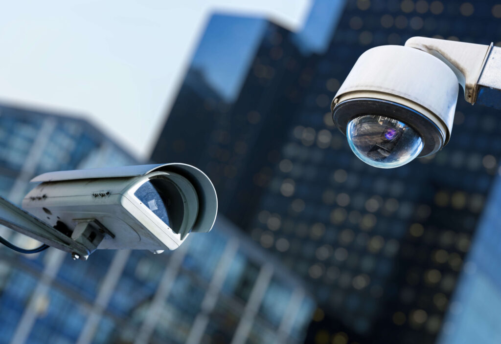 Duas câmeras de segurança CFTV instaladas ao ar livre, representando monitoramento profissional para empresas e hotelaria