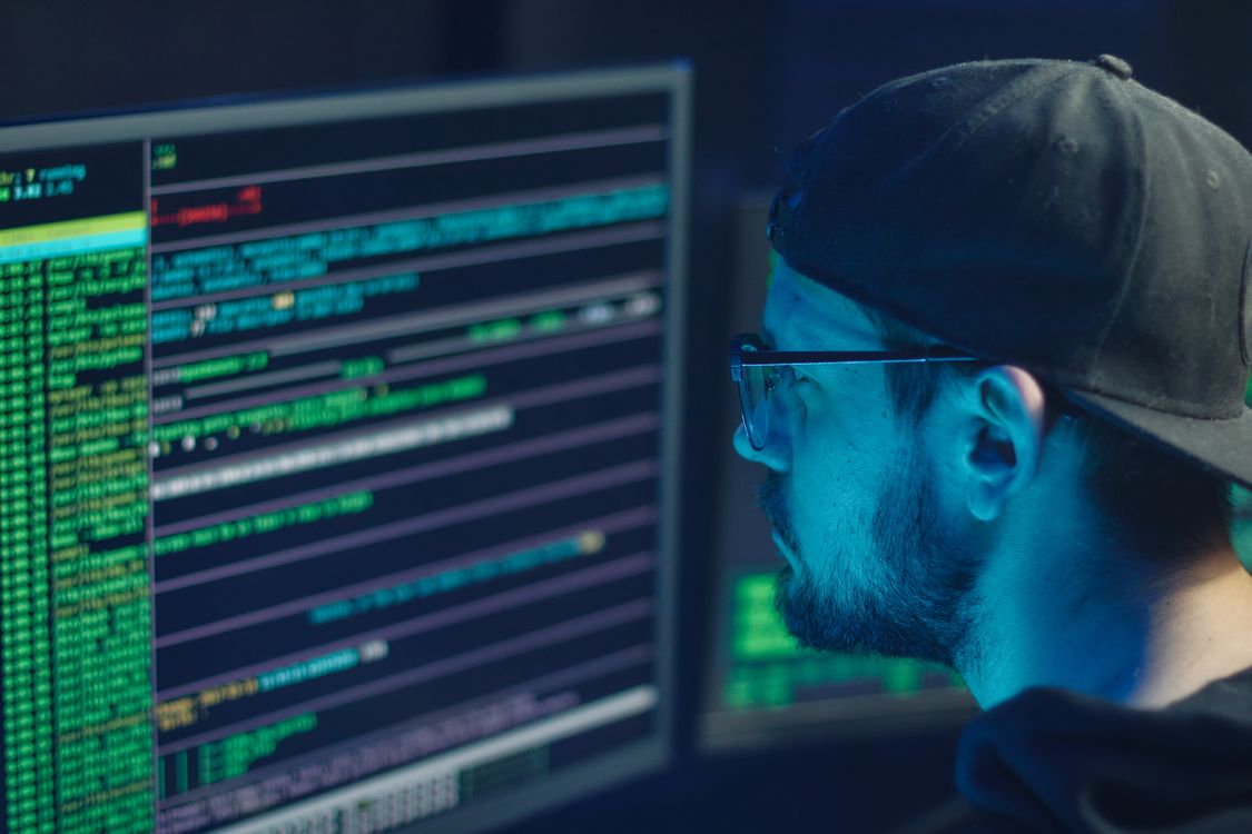 Profissional de segurança da informação analisando múltiplos monitores em ambiente técnico contemporâneo